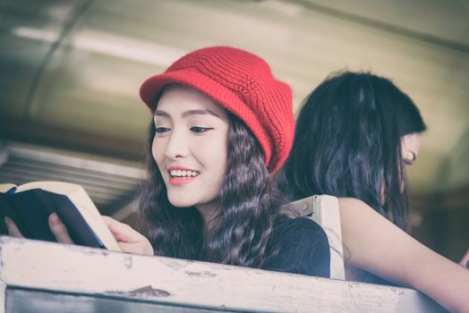 Asian women traveler have reading a book and talking in the train with happiness at Hua Lamphong station at Bangkok, Thailand.