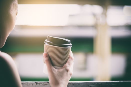 Asian woman traveler has drinking coffee in the train with happiness at Hua Lamphong station at Bangkok, Thailand.