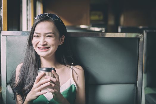 Asian woman traveler has drinking coffee in the train with happiness at Hua Lamphong station at Bangkok, Thailand.