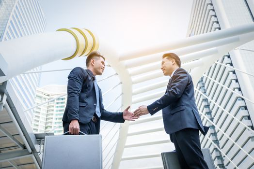 Two asian business have handshake with building and city background.