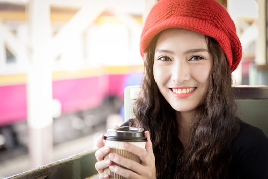 Asian woman traveler has drinking a cup of coffee with traveling by train at Hua Lamphong station at Bangkok, Thailand.