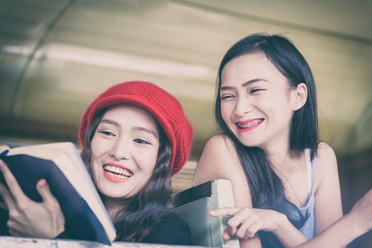 Asian women traveler have reading a book and talking in the train with happiness at Hua Lamphong station at Bangkok, Thailand.