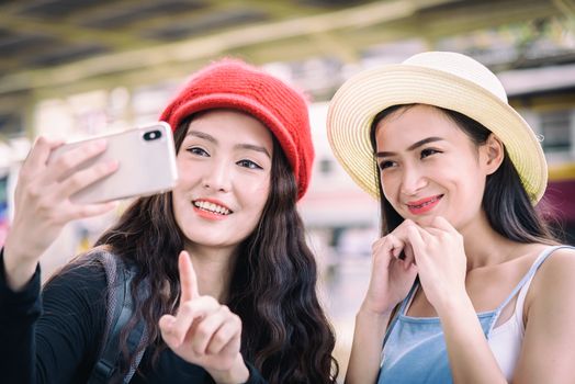 Asian women traveler have playing a mobile phone and talking for waiting the train with happiness at Hua Lamphong station at Bangkok, Thailand.