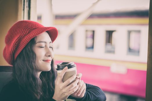 Asian woman traveler has drinking a cup of coffee with traveling by train at Hua Lamphong station at Bangkok, Thailand.