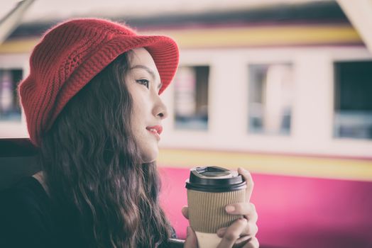 Asian woman traveler has drinking a cup of coffee with traveling by train at Hua Lamphong station at Bangkok, Thailand.