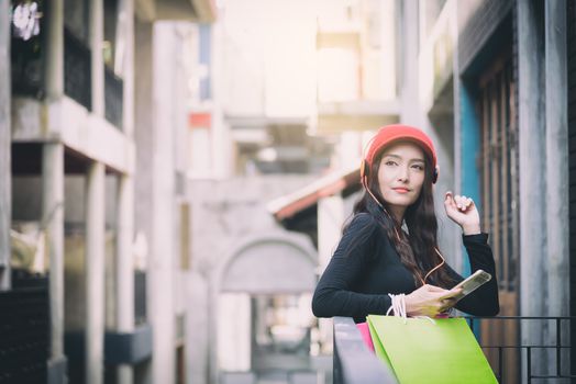 Asian portrait girl has happy and listening music with shopping colorful bags.