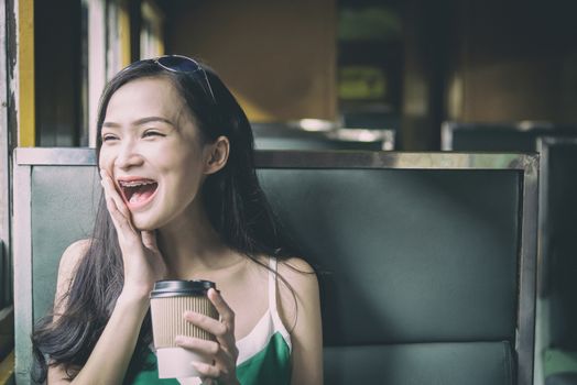 Asian woman traveler has drinking coffee in the train with happiness at Hua Lamphong station at Bangkok, Thailand.