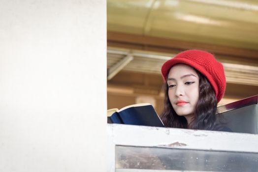 Asian woman traveler has reading a book in the train with happiness at Hua Lamphong station at Bangkok, Thailand.