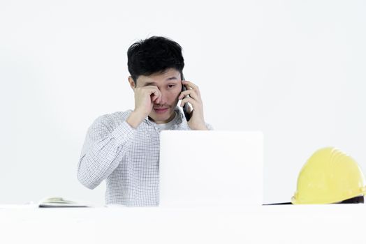 Asian employee engineer salary man sitting at desk and talking with phone and feeling sleepy, isolated on white background.