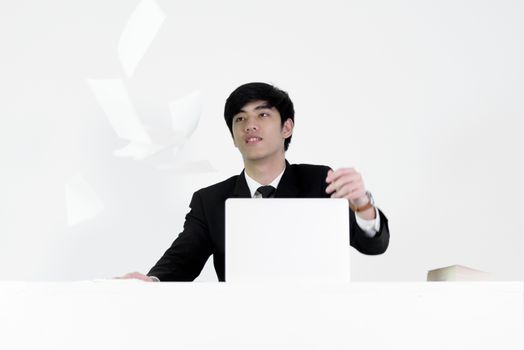 Asian manager businessman sitting at desk throwing papers with feeling angry and upset, isolated on white background.