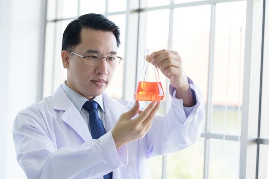 Asian Laboratory scientist man working at lab with test red tubes.