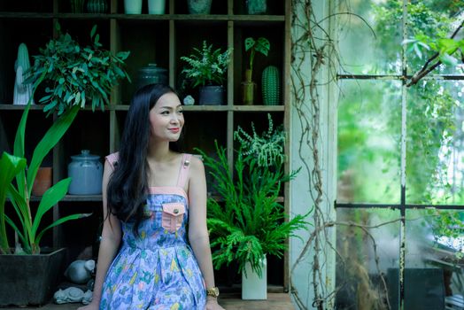 Asian pretty girl has relaxing with happy and smiling at Little Tree Garden cafe, Nakhon Pathom province, Thailand in the morning.