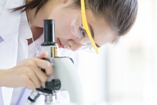 Asian young student scientist researching with a microscope in a laboratory.