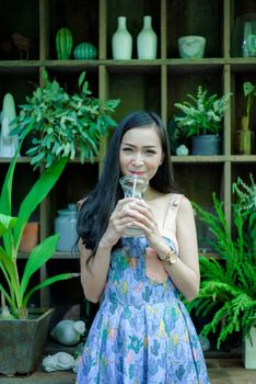 Asian pretty girl has drinkling ice white milk with happy and smiling at Little Tree Garden cafe, Nakhon Pathom province, Thailand in the morning.