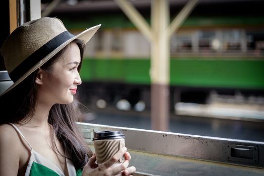 Asian woman traveler has drinking coffee in the train with happiness at Hua Lamphong station at Bangkok, Thailand.