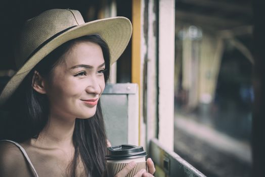 Asian woman traveler has drinking coffee in the train with happiness at Hua Lamphong station at Bangkok, Thailand.