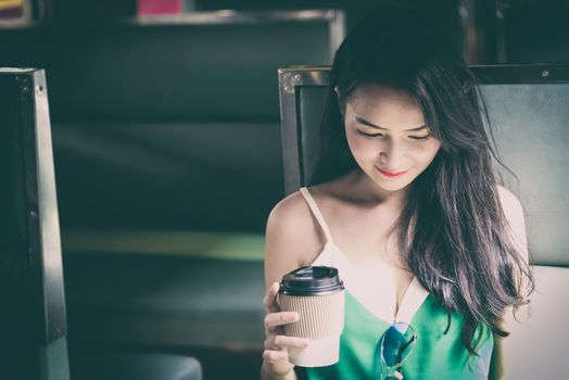 Asian woman traveler has drinking coffee in the train with happiness at Hua Lamphong station at Bangkok, Thailand.