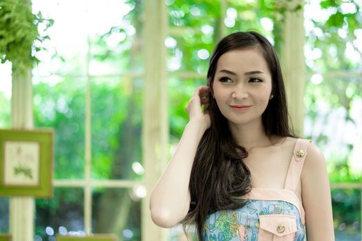 Asian pretty girl has relaxing with happy and smiling at Little Tree Garden cafe, Nakhon Pathom province, Thailand in the morning.