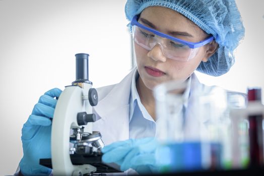 Asian yound student scientist researching with a microscope in a laboratory.