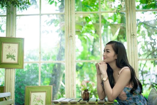 Asian pretty girl has relaxing with happy and smiling at Little Tree Garden cafe, Nakhon Pathom province, Thailand in the morning.