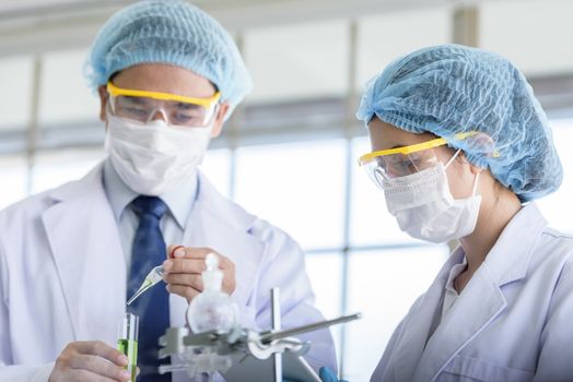 Asian senior scientist have teaching young student scientist in a laboratory.