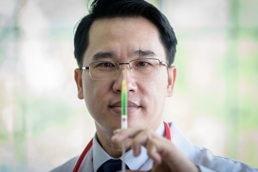 Professional asian doctor with green syringe and splashing.