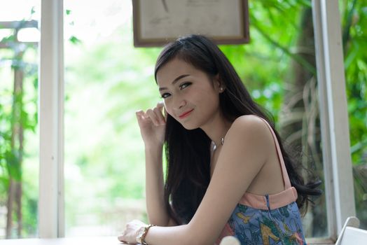 Asian pretty girl has relaxing with happy and smiling at Little Tree Garden cafe, Nakhon Pathom province, Thailand in the morning.