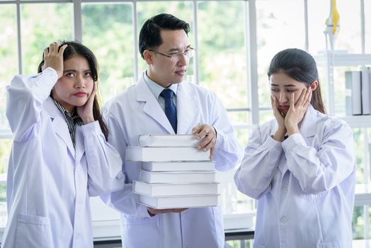 Senior asian scientist has assigning new job to students in laboratory.