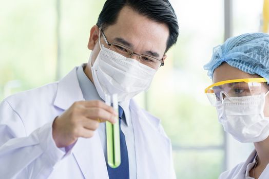 Asian senior scientist have teaching young student scientist in a laboratory.