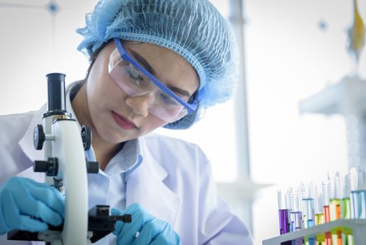 Asian yound student scientist researching with a microscope in a laboratory.