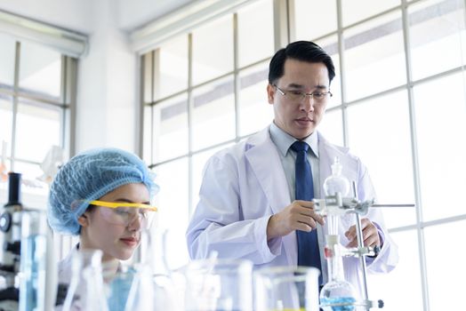 Asian senior scientist have teaching young student scientist in a laboratory.