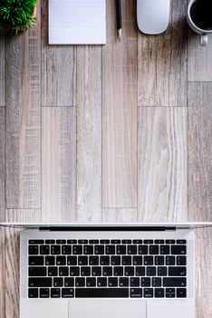 The office desk flat lay view with laptop, mouse, tree, black clip, coffee cup, notebook, pencil on wood texture background.