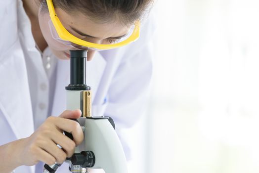 Asian young student scientist researching with a microscope in a laboratory.