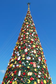 Tall green Christmas tree with shapes and gifts decoration during holiday season in the park