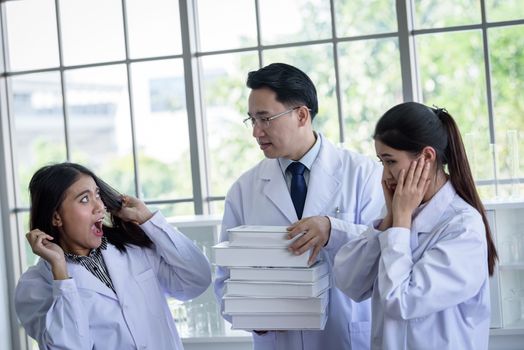 Senior asian scientist has assigning new job to students in laboratory.