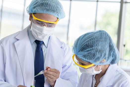 Asian senior scientist have teaching young student scientist in a laboratory.