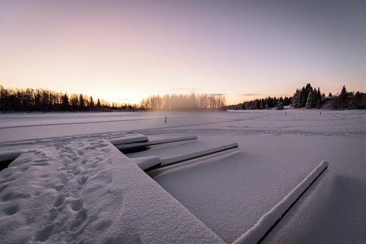 The ice lake and forest has covered with heavy snow and nice blue sky in winter season at Holiday Village Kuukiuru, Finland.