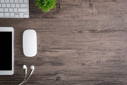 The office desk flat lay view with keyboard, mouse, tree and earphone on wood texture background.