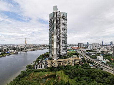 The high condominium nearby river and city with cloudy and blue sky at Bangkok, Thailand.