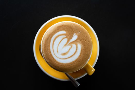 A cup of coffee with beautiful latte art on black table background.