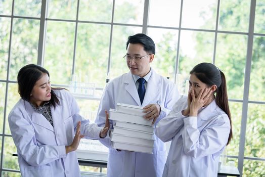 Senior asian scientist has assigning new job to students in laboratory.