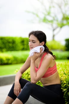Beautiful woman runner has used a white towel wipe her face after running in the garden.