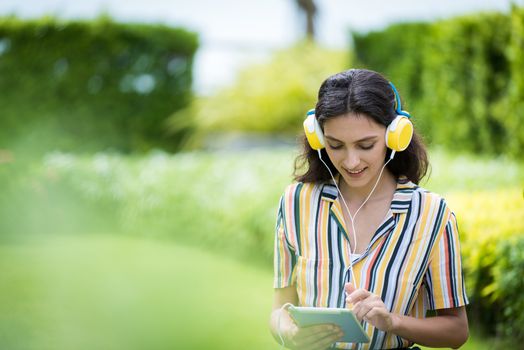 Portrait of a beautiful woman has listening to music with smiling and relax in the garden.