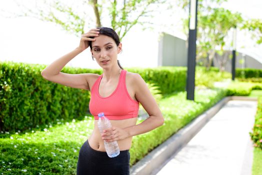 Beautiful woman runner has drinking water in the garden.