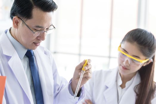 Asian senior scientist have teaching young student scientist in a laboratory.