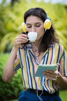 Portrait of a beautiful woman has drunk a coffee and listening to music with smiling and relax in the garden.