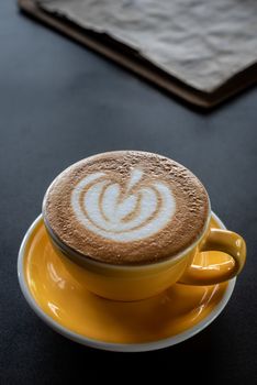 A cup of coffee with beautiful latte art and drink menu on black table background.