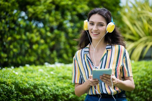 Portrait of a beautiful woman has listening to music with smiling and relax in the garden.