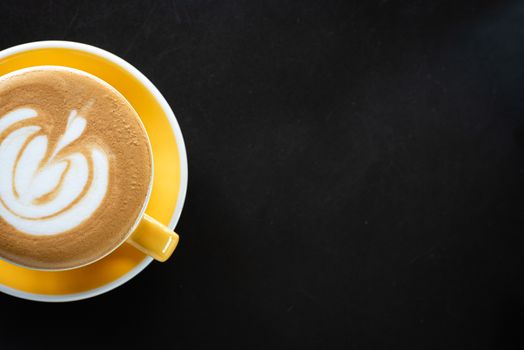 A cup of coffee with beautiful latte art on black table background.