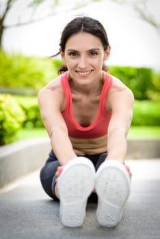 Beautiful woman runner has to warm up with stretching in the garden.